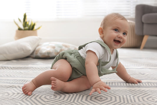 baby smiling on rug in green romper